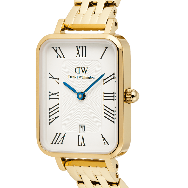 Close-up of the Quadro Roman Numerals Date 5-link Gold ladies watch showing the rectangular white guilloché dial, black Roman numerals, blue hands, date window, and polished gold bracelet.