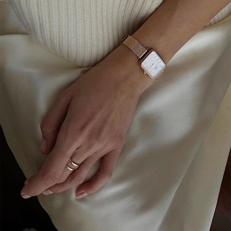 A woman’s hand wearing the Elan Dual Ring Rose Gold, styled with a matching rose gold watch, highlighting the ring’s double-band design and minimalist elegance for everyday wear.