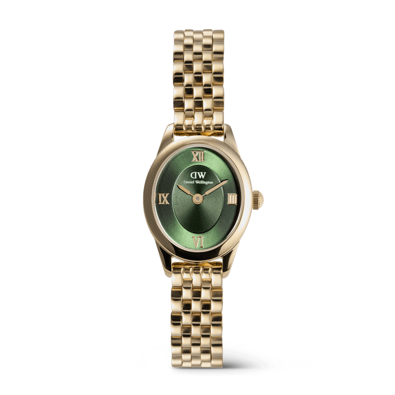 A petite gold women’s watch with an oval case, emerald green sunray dial, gold Roman numerals, and a polished gold beans link bracelet.
