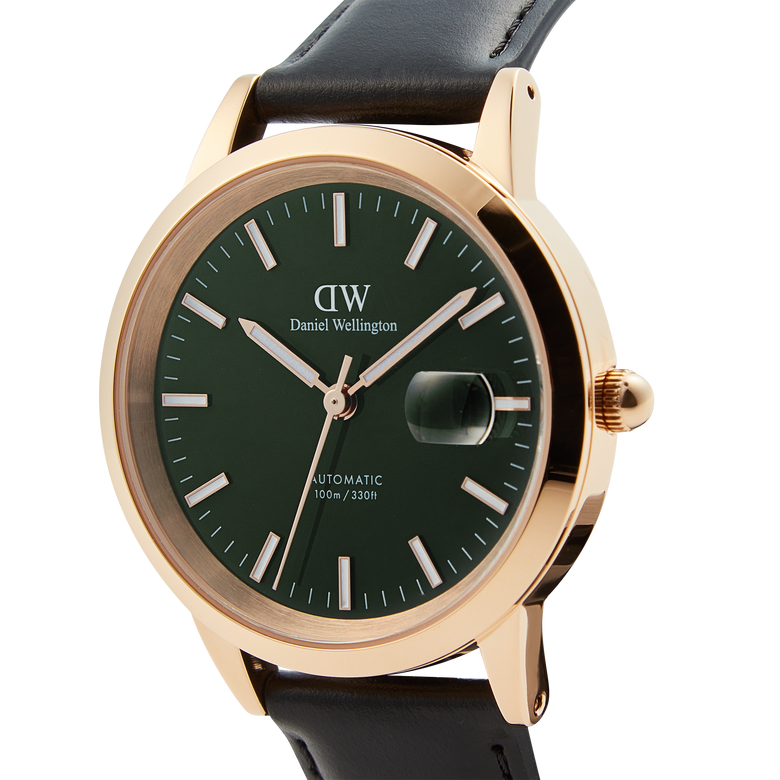 Close-up of the Daniel Wellington Iconic Sheffield Automatic Rose Gold watch, showing its emerald green enamel dial, rose gold case, luminous markers, and black leather strap.