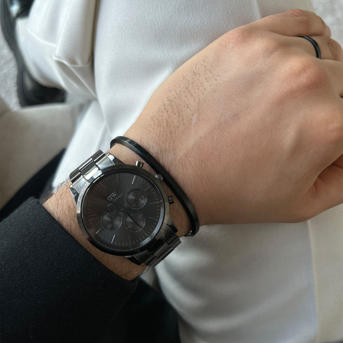 Classic Ring Black worn on a man's finger, styled with a matching black bracelet and stainless steel watch, highlighting its minimalist design and versatile appeal for everyday wear.