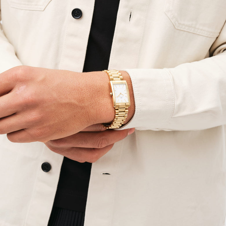 Bound 3-Link Gold wristwatch with a rectangular gold case and white dial, worn with a cream shirt for a stylish and versatile everyday look.