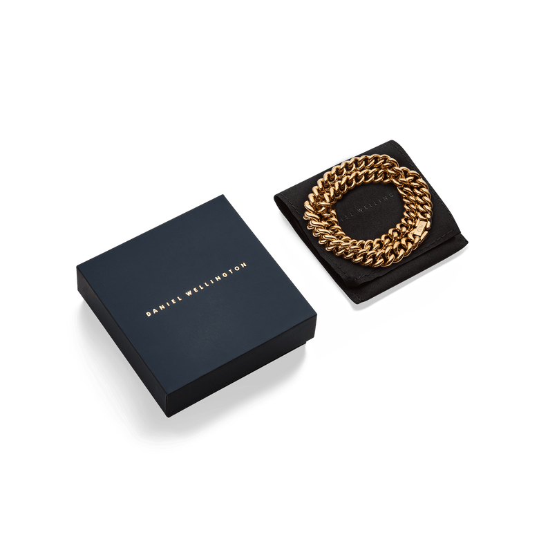 Chunky Chain Necklace Gold presented coiled on a black cushion next to a sleek Daniel Wellington gift box, showcasing its bold gold links and elegant packaging ideal for gifting.