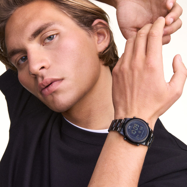 Daniel Wellington Retro Digital Dark Grey Dark Grey watch worn on the wrist, showing its bold dark grey finish, digital display, and transparent bio-based plastic link strap paired with a casual black T-shirt.