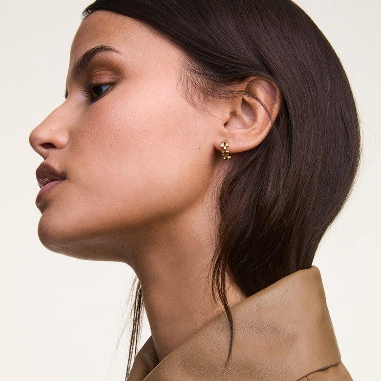 A woman wearing Daniel Wellington 3-Link Earrings Gold, featuring a geometric open link design in polished gold, styled with a neutral-toned outfit for a modern and understated look.