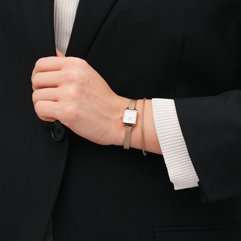 A woman wearing the Tide Mesh Bracelet Melrose 1.8 in rose gold, styled alongside a matching rose gold watch, with both accessories complementing a formal black blazer and white top.