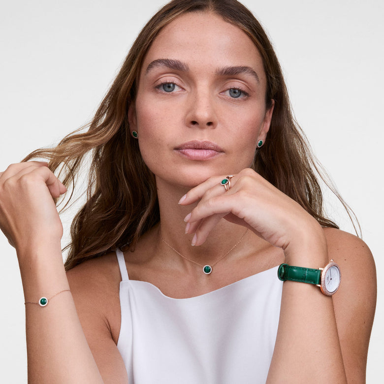 A woman wearing the Audrey Necklace Malachite Rose Gold, styled with a matching malachite bracelet and green strap watch, highlighting the elegant rose gold chain and domed malachite pendant with cubic zirconia accents.
