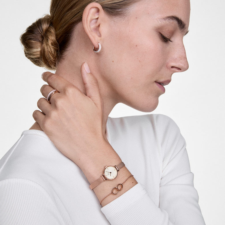 A woman wearing the Petite Mini & Elan Unity Bracelet Set Rose Gold, featuring a slim rose gold ladies watch with a mesh strap and a delicate rose gold bracelet with interlocking rings, styled with a white top for an elegant, minimalist look.
