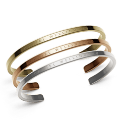Three minimalist cuff bracelets in rose gold, gold, and silver tones, each engraved with the Daniel Wellington logo, displayed together to highlight their polished stainless steel finish and versatile styling.