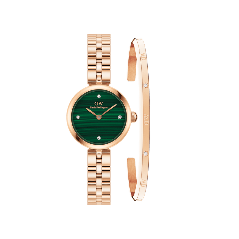 Rose gold Daniel Wellington watch with a deep green malachite dial and matching rose gold link strap, paired with a slim rose gold bracelet featuring crystal accents for a refined, coordinated look.