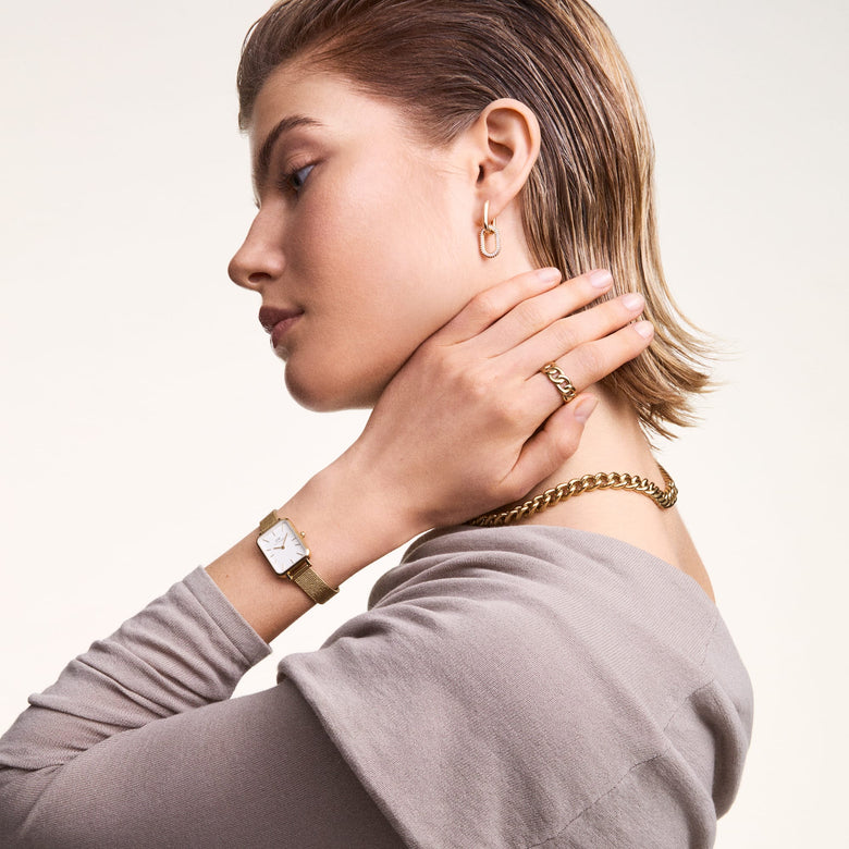 Quadro Pressed Evergold Gold watch styled on a woman's wrist, paired with gold jewellery, highlighting its rectangular white dial and gold mesh bracelet for a sophisticated everyday look.
