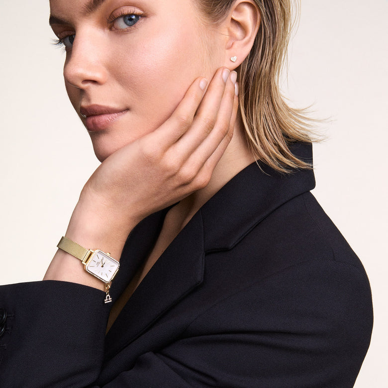 Crystal Heart Stud Silver earring worn on the ear, featuring a petite heart shape with sparkling cubic zirconia crystals, styled with a smart black blazer for a polished and elegant look.