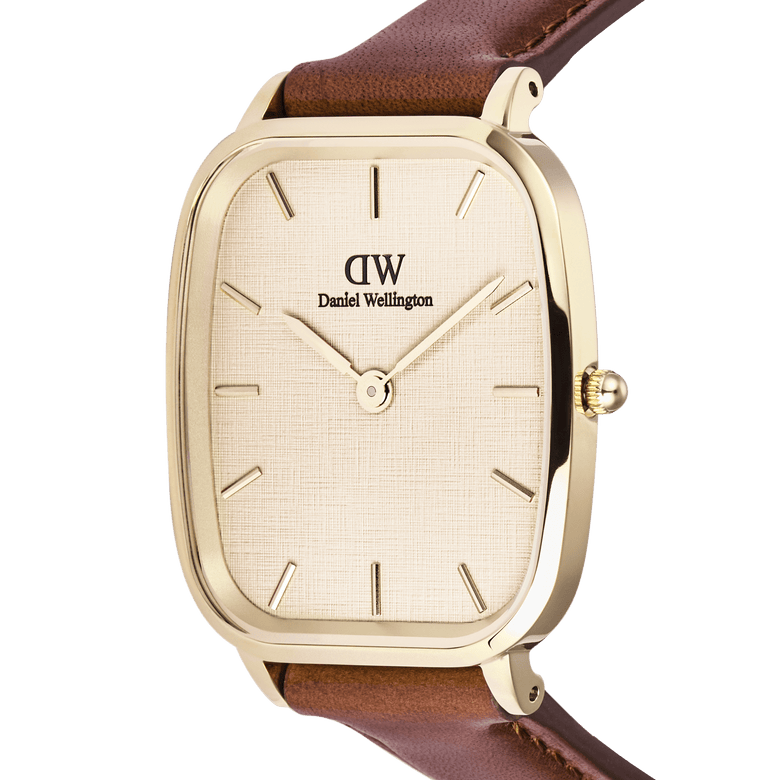 Close-up of the Daniel Wellington Marlon St Mawes Linen Gold men’s watch, featuring a cushion-shaped gold case, linen-textured dial, minimalist gold-tone hour markers, and a brown leather strap.
