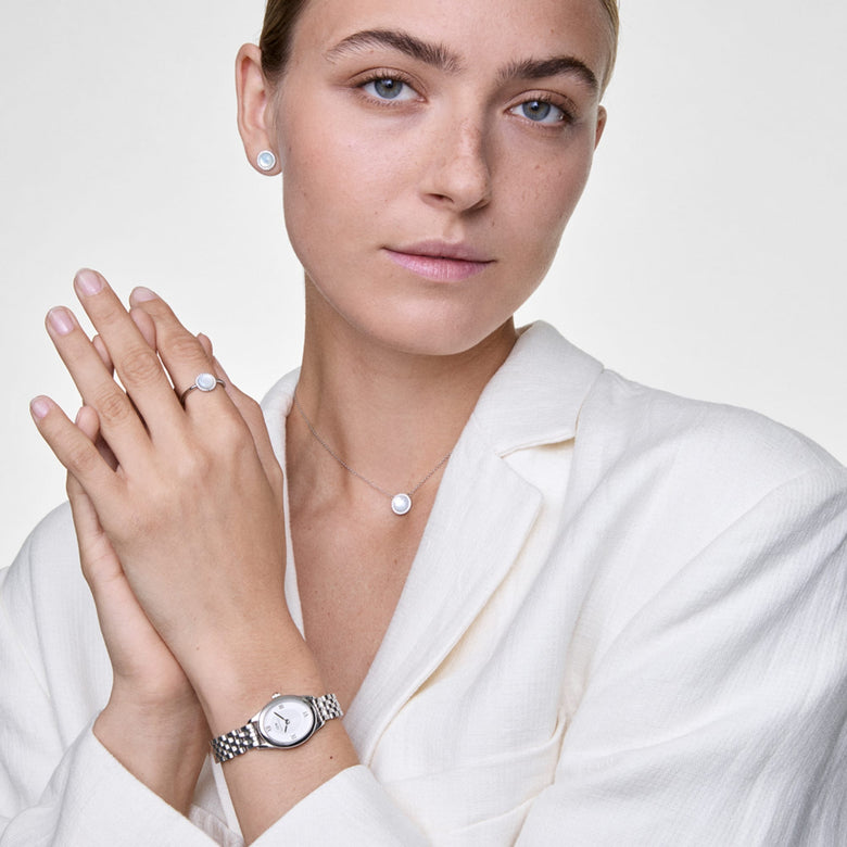 A woman wearing the Ophelia Mini Silver watch with a polished silver oval case and 5-link bracelet, styled with matching silver jewellery and a light textured blouse for an elegant, everyday look.