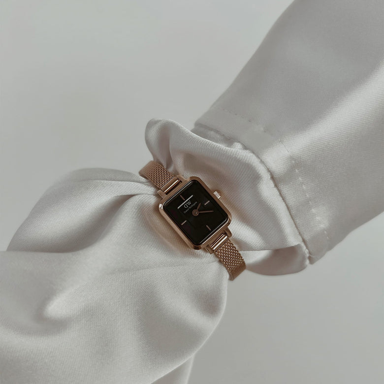 Quadro Mini Melrose Onyx ladies watch with a rectangular black dial and rose gold mesh strap, worn on the wrist with a white long sleeve, showcasing its slim profile and elegant styling for everyday wear.