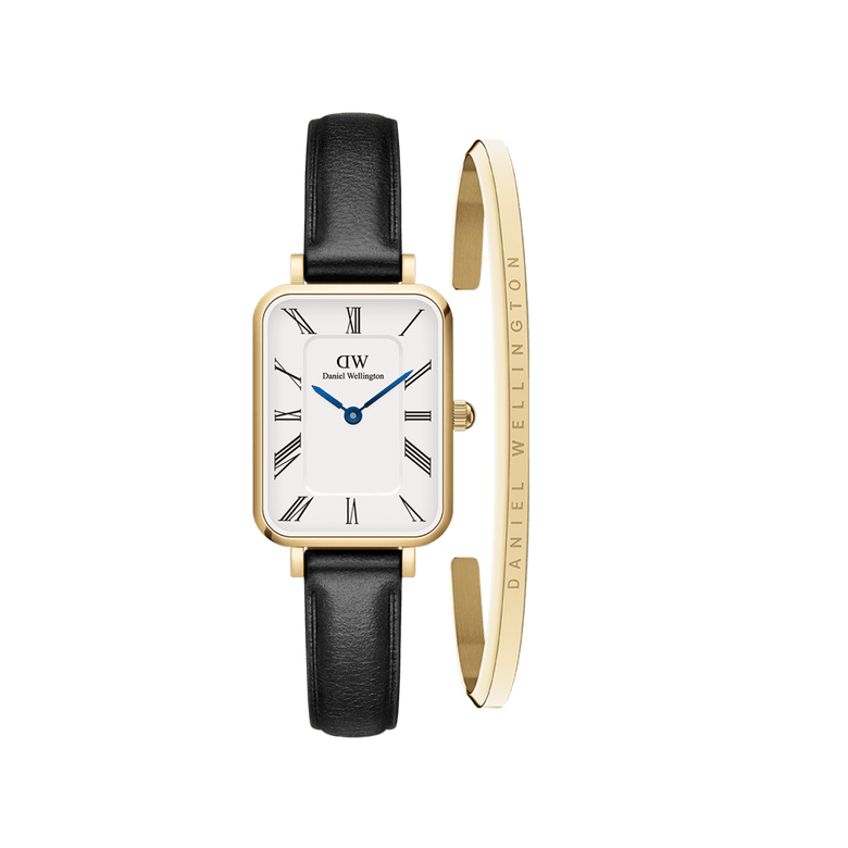 Rectangular gold-framed watch with a white dial, black Roman numerals, blue hands, and a black leather strap, paired with a slim gold bracelet engraved with the Daniel Wellington name.