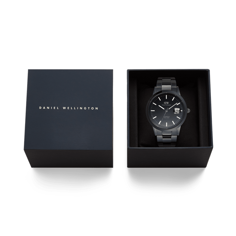 Daniel Wellington Iconic Link Automatic Black watch with a black stainless steel bracelet, presented in its branded gift box with the lid beside it.