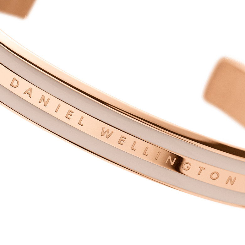 Emalie Bracelet Desert Sand Rose Gold close-up showing the engraved Daniel Wellington branding, rose gold finish, and desert sand enamel detail on the cuff.