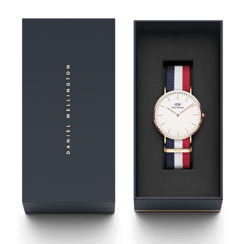 Classic Cambridge Rose Gold watch with a striped blue, white, and red NATO strap, presented in a sleek Daniel Wellington gift box.