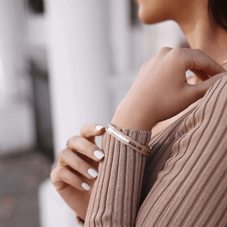 Emalie Bracelet Desert Sand Rose Gold worn on a woman’s wrist, showing its rose gold and desert sand enamel cuff paired with a neutral ribbed top for a stylish, everyday look.