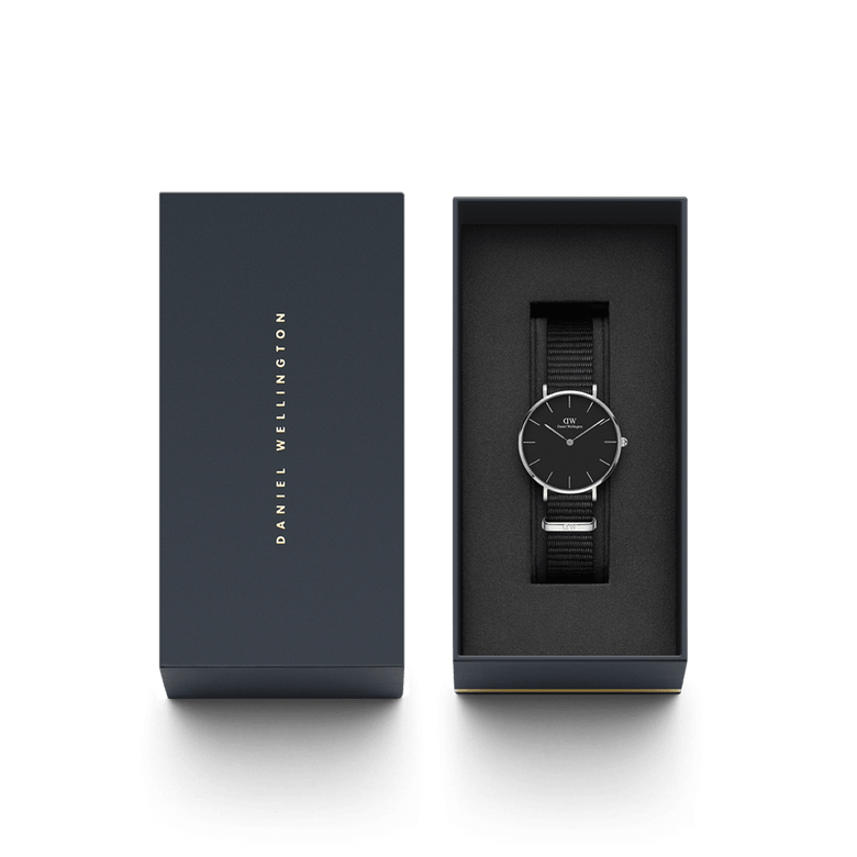 Petite Cornwall Black Silver watch with a black dial and silver case, presented in a dark Daniel Wellington gift box with foam padding for protection.