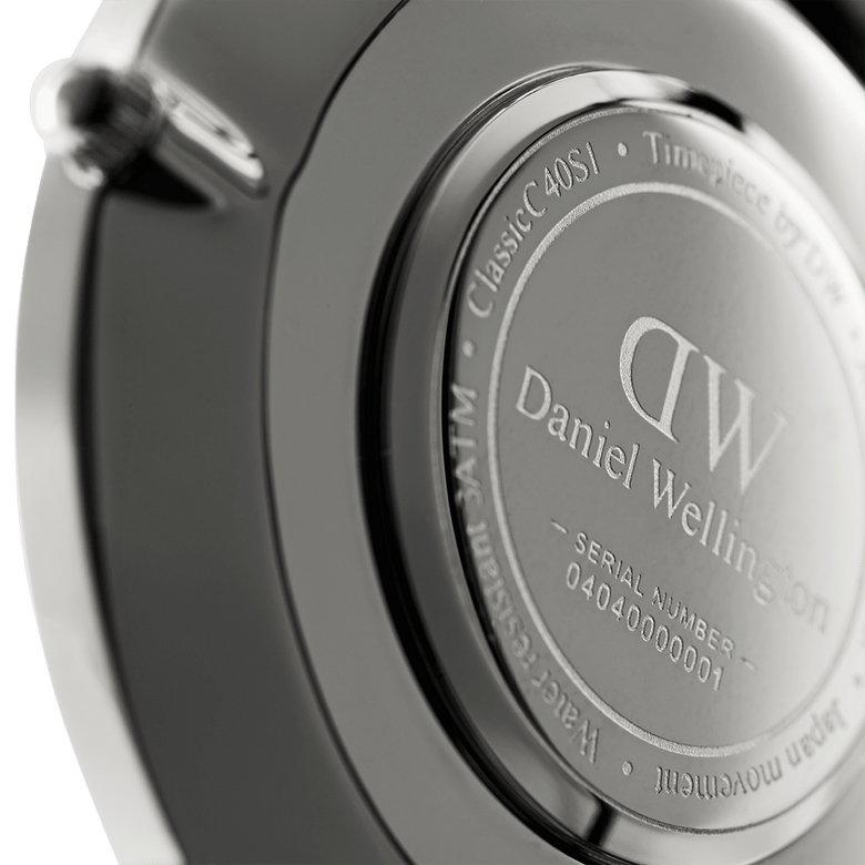 Close-up of the Classic Sheffield Silver watch case back, showing the engraved Daniel Wellington branding, water resistance rating, and unique serial number on the stainless steel surface.
