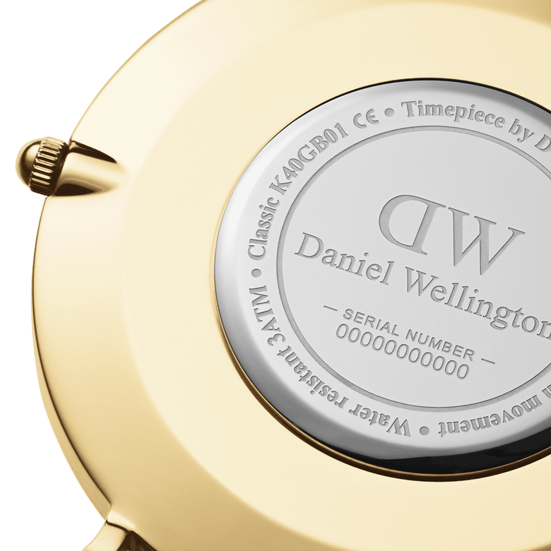 Close-up of the Classic St Mawes Gold watch case back, showing the engraved Daniel Wellington branding, serial number, and water resistance details on a gold-plated stainless steel finish.