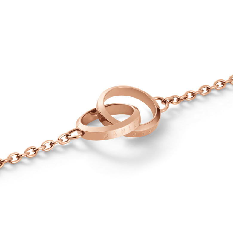 Close-up of the Elan Unity Bracelet Rose Gold showing two polished interlocking rings engraved with branding, attached to a fine rose gold chain.