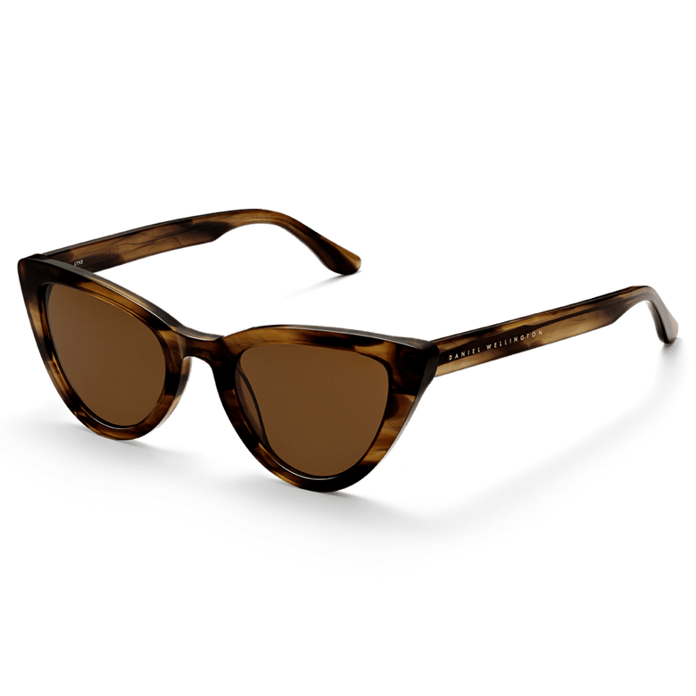 Lynx Bio-Acetate Brown Demi sunglasses with a cat eye silhouette, featuring a brown demi frame, amber lenses, and Daniel Wellington branding on the arm.