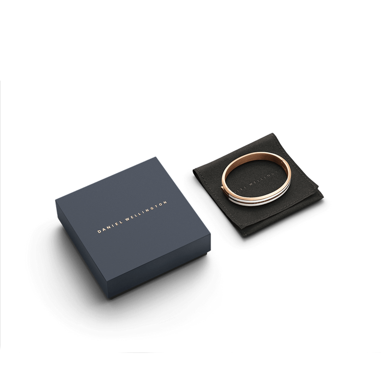 Emalie Infinite Rose Gold Satin White bangle presented on a black pouch next to a navy Daniel Wellington gift box, showcasing its elegant rose gold and white enamel design.