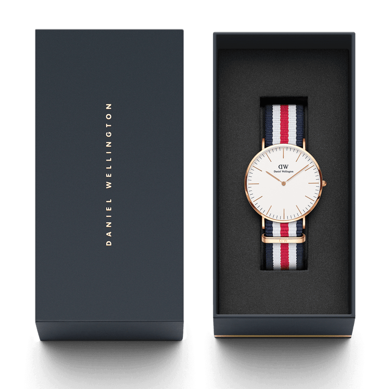 Classic Canterbury Rose Gold watch with a blue, white, and red striped NATO strap, presented in a sleek Daniel Wellington gift box.