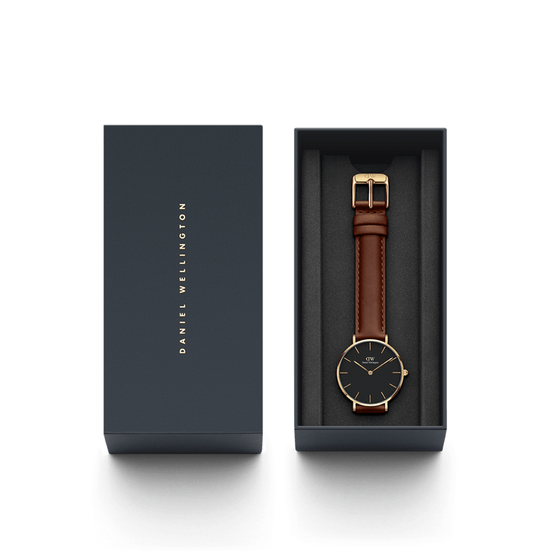 Petite St Mawes Black Gold watch presented in a sleek Daniel Wellington gift box, featuring a gold-plated case, black dial, and brown leather strap for elegant gifting or personal use.