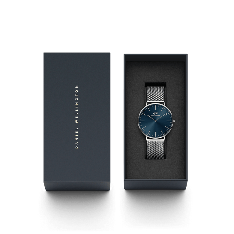 Classic Mesh Arctic Silver watch with a blue sunray dial and silver mesh strap, neatly presented in a dark Daniel Wellington gift box, ideal for gifting or special occasions.