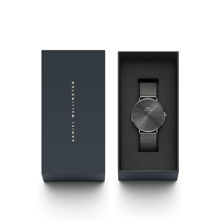 Classic Mesh Graphite watch with a graphite grey stainless steel mesh strap and minimalist sunray dial, elegantly presented in a dark gift box with Daniel Wellington branding.
