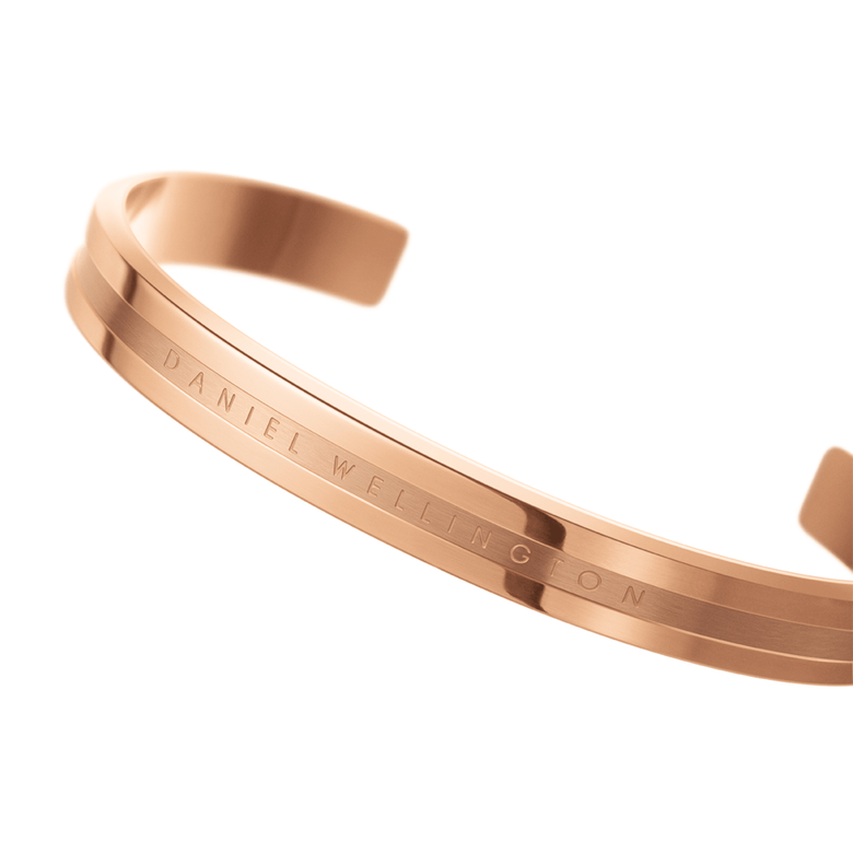 Close-up of the Elan Bracelet Rose Gold by Daniel Wellington, showing its polished rose gold finish, minimalist lines, and engraved logo on the open cuff.