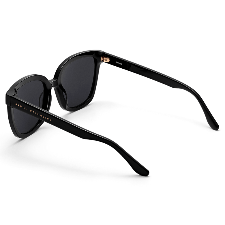 Grande Bio-Acetate Black sunglasses featuring a bold square frame, glossy black finish, and Daniel Wellington branding on the temples, shown from a rear angle highlighting the sturdy construction.