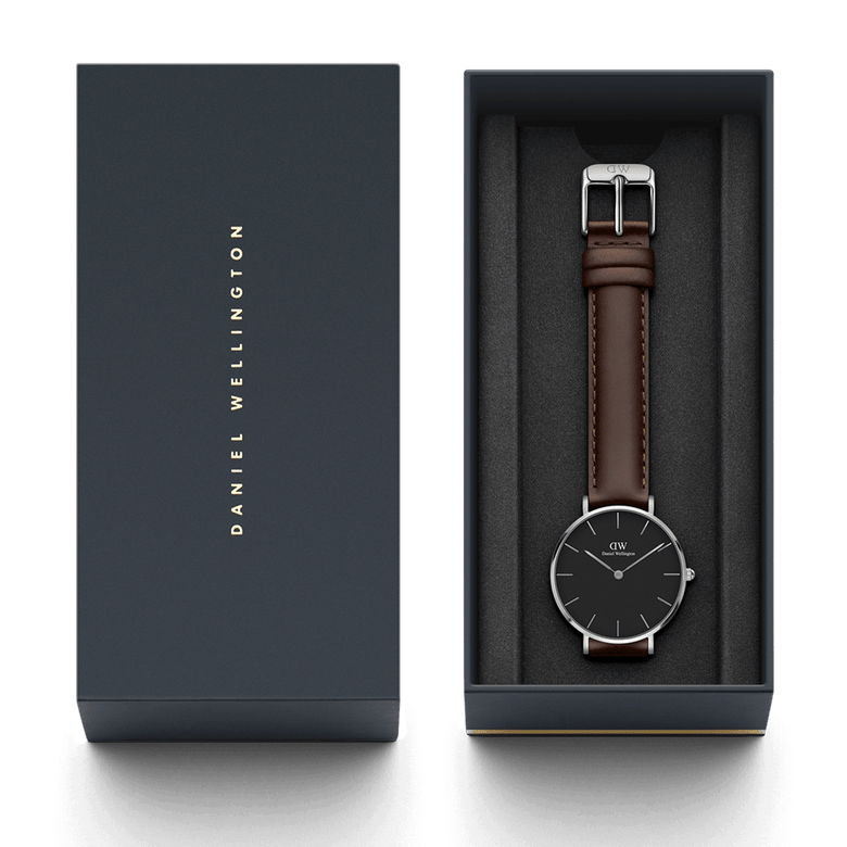 Petite Bristol Black Silver watch with a dark brown leather strap and minimalist black dial, elegantly presented in a Daniel Wellington branded gift box.