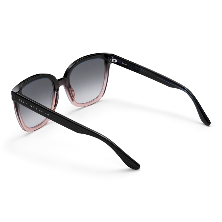 Grande Bio-Acetate Blue Coral Blue sunglasses with a bold square frame, dark blue to coral gradient detailing, black gradient lenses, and Daniel Wellington branding on the arms.